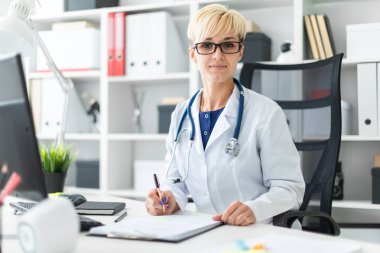 bir beyaz genç kadın doktor robe oturma masa ve dolgular bir belge 