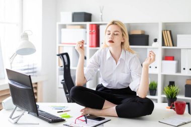oturma ve ofiste bir tablo üzerinde meditasyon genç iş kadını.