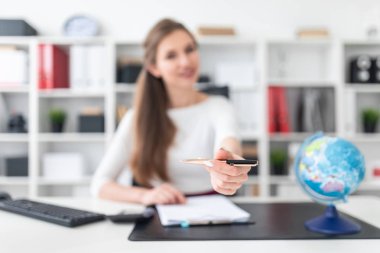 Genç bir kız bilgisayar near Danışma standları ve beyaz bir levha ile bir tablet tutar.