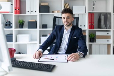 Genç bir adam ofiste bir tabloda yakın duran, telefonda konuşurken ve metin klavyede yazma.