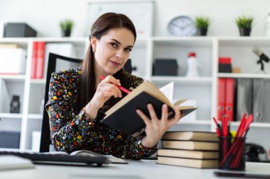 economist with pen in hand attentively reading business book and sitting at table in bright office 