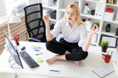 oturma ve ofiste bir tablo üzerinde meditasyon genç iş kadını.