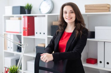 Parlak bir ofiste çalışan güzel bir genç kız. Bir genç kız kırmızı bir elbise ve siyah bir ceket. 