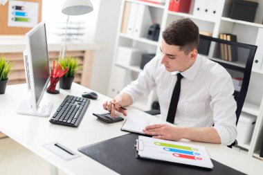 young businessman working at a table in the office with documents and a computer clipart