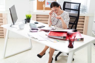 Bilgisayar masasında ofiste bir sandalyede oturan bir genç kız.