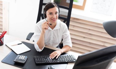 Genç bir kız ile bir bilgisayar masada oturan bir mikrofon kulaklık.