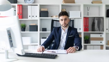 Genç bir adam ofiste bir tabloda yakın duran, telefonda konuşurken ve metin klavyede yazma.