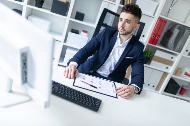 Genç bir adam ofiste bir tabloda yakın duran, telefonda konuşurken ve metin klavyede yazma.