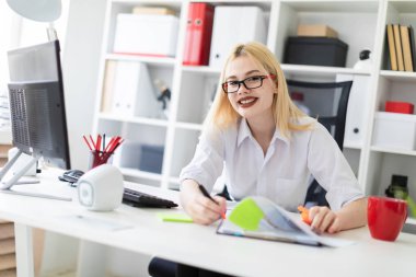 bir bilgisayar ve belgeler ile ofiste çalışan genç iş kadını.