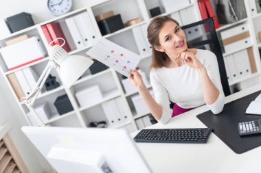 Genç bir kız bilgisayar near Danışma standları ve beyaz bir levha ile bir tablet tutar.