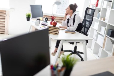 Güzel bir genç kız bir grup başında beyaz gömlek ve siyah yelek ile parlak bir ofiste çalışıyor. alan derinliği ile fotoğraf