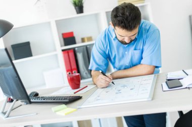 ofiste genç adam bir masada oturur ve belgeleriyle çalışır.