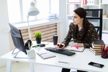 Masada oturan ve bir bilgisayar ile çalışan genç kız
