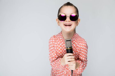 Kız mikrofona bir gri arka plan şarkı üzerinde.