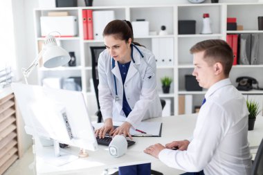 Sorun bilgisayarda Office hastaya açıklayan boynuna phonendoscope ile genç doktor