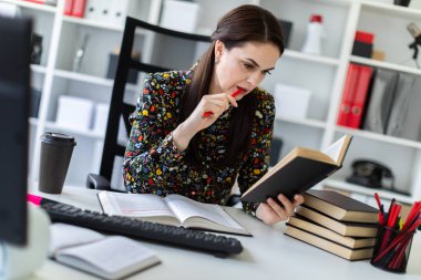 economist with pen in hand attentively reading business book and sitting at table in bright office 