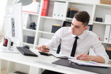 bilgisayarda ofis masasında oturan ve belgelerle çalışma genç işadamı.