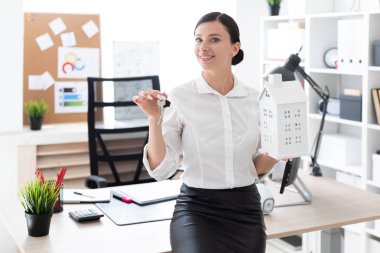 Genç bir kız ofiste ayakta ve tutmak belgili tanımlık anahtar taşı ve evin düzeni.