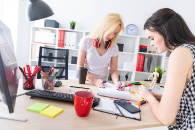 İki kız ofiste çalışmak. Kız bir adam bir modeli tutuyor.