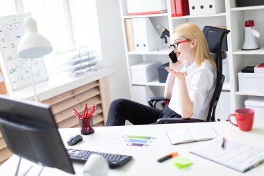 ofiste oturan ve bir telefon tutarak genç iş kadını