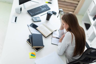 Tablo ve bir bilgisayar, belge ve hesap makinesi ile çalışır bir genç kız oturdu