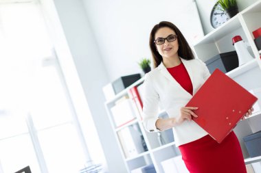 ofiste duran ve bir klasör tutan genç kız. 