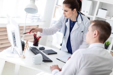 Bilgisayar ekranında işaret ve hastaya Office sorunu açıklayan laboratuar önlüğünü genç doktor 
