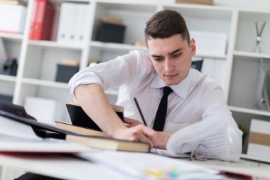 genç işadamı bir kitap, belgeler ve bir bilgisayar ile ofiste bir masada çalışma