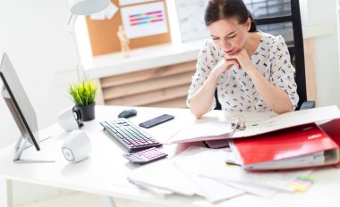 Bilgisayar masasında ofiste bir sandalyede oturan bir genç kız.