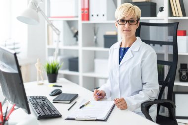 bir beyaz genç kadın doktor robe oturma masa ve dolgular bir belge 