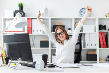 Genç kız ofiste bir bilgisayar masasında oturan ve ellerini kaldırdı