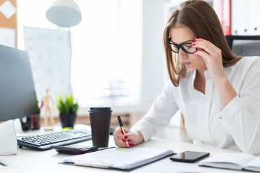 Genç kız masada oturan ve bir bilgisayar ve kahve ile çalışan