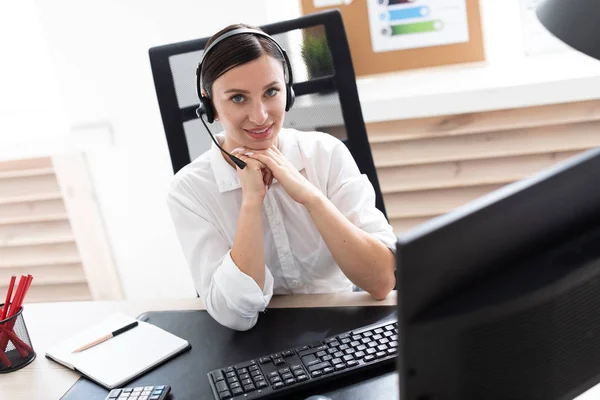 A young girl in headphones with a microphone sitting at a computer table. — Stock Photo, Image