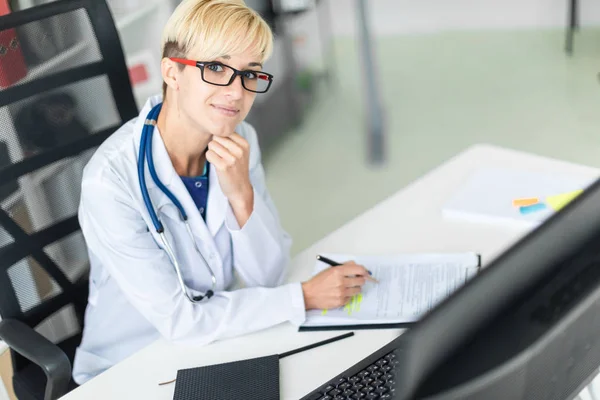 Joven Doctora Vestida Con Una Bata Blanca Sentada Mesa Llena — Foto de Stock