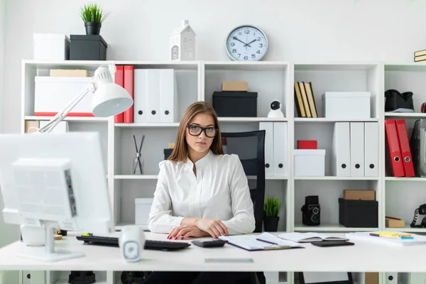 Een jong meisje ging zitten op de tabel en werkt met een computer, documenten en calculator — Stockfoto