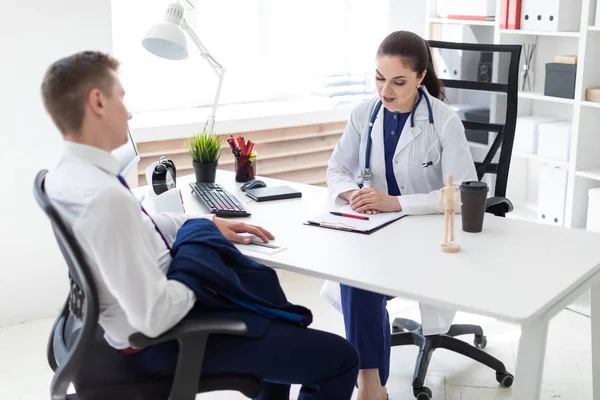 doctor interviewing young patient while sitting at table in office