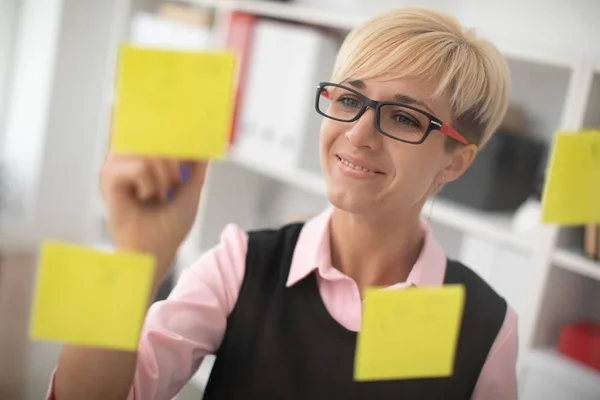 young woman  stands in the office near a transparent Board with stickers