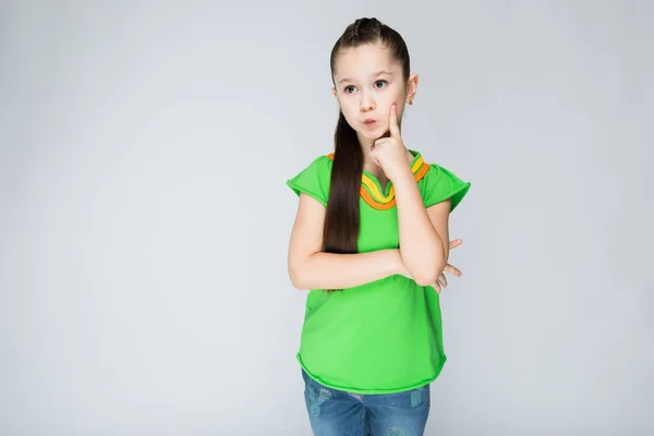 Meisje Een Grijze Achtergrond Met Haar Vinger Haar Wang — Stockfoto