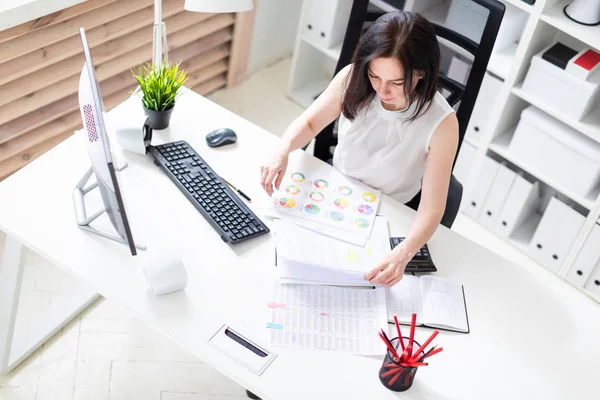 Een jong meisje zittend op kantoor op een computer Desk en werken met documenten en een rekenmachine. — Stockfoto