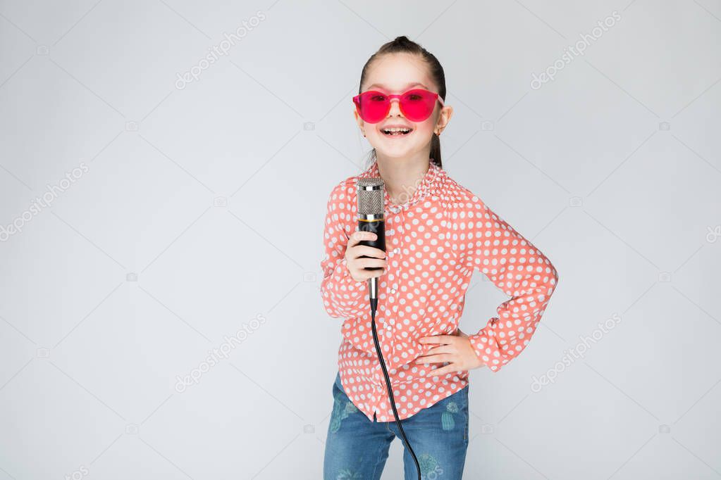 Girl on a gray background singing into the microphone.