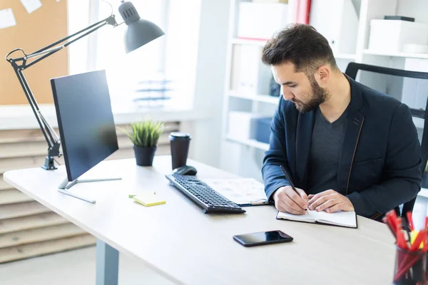 El joven trabaja en la oficina en una computadora Escritorio con documentos, diagramas y teléfono . — Foto de Stock