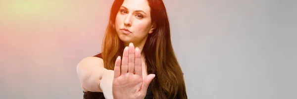 Emocional bastante confiado modelo serio más tamaño de pie en el estudio mostrando señal de stop sobre fondo gris —  Fotos de Stock