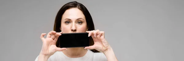 Mujer joven presentando teléfono — Foto de Stock