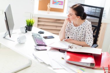 Office belgeleriyle çalışma ve çenesine kadar propped masası, bilgisayar başında oturan bir genç kız.