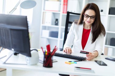 Office masada oturan ve bir banka kartı tutan genç bir kız.