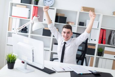 Bilgisayarda ofis masasında oturan ve ellerini kaldırdı genç bir adam.