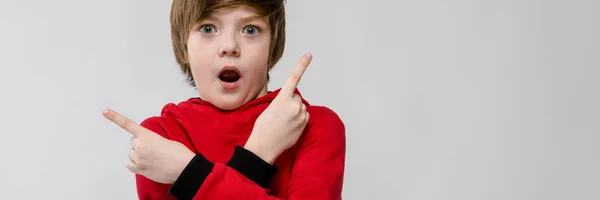 Bonito confiante engraçado surpreendido pouco caucasiano menino com boca aberta em camisola vermelha no fundo cinza — Fotografia de Stock