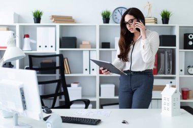 Bir genç kız masanın ayakta ve telefonda konuşurken.