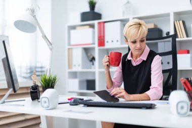 Office masada oturan ve kahve içme kız.