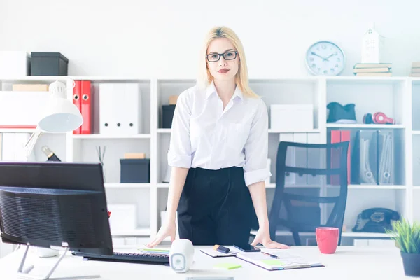 Una chica joven parada en la oficina en la mesa de la computadora . — Foto de Stock